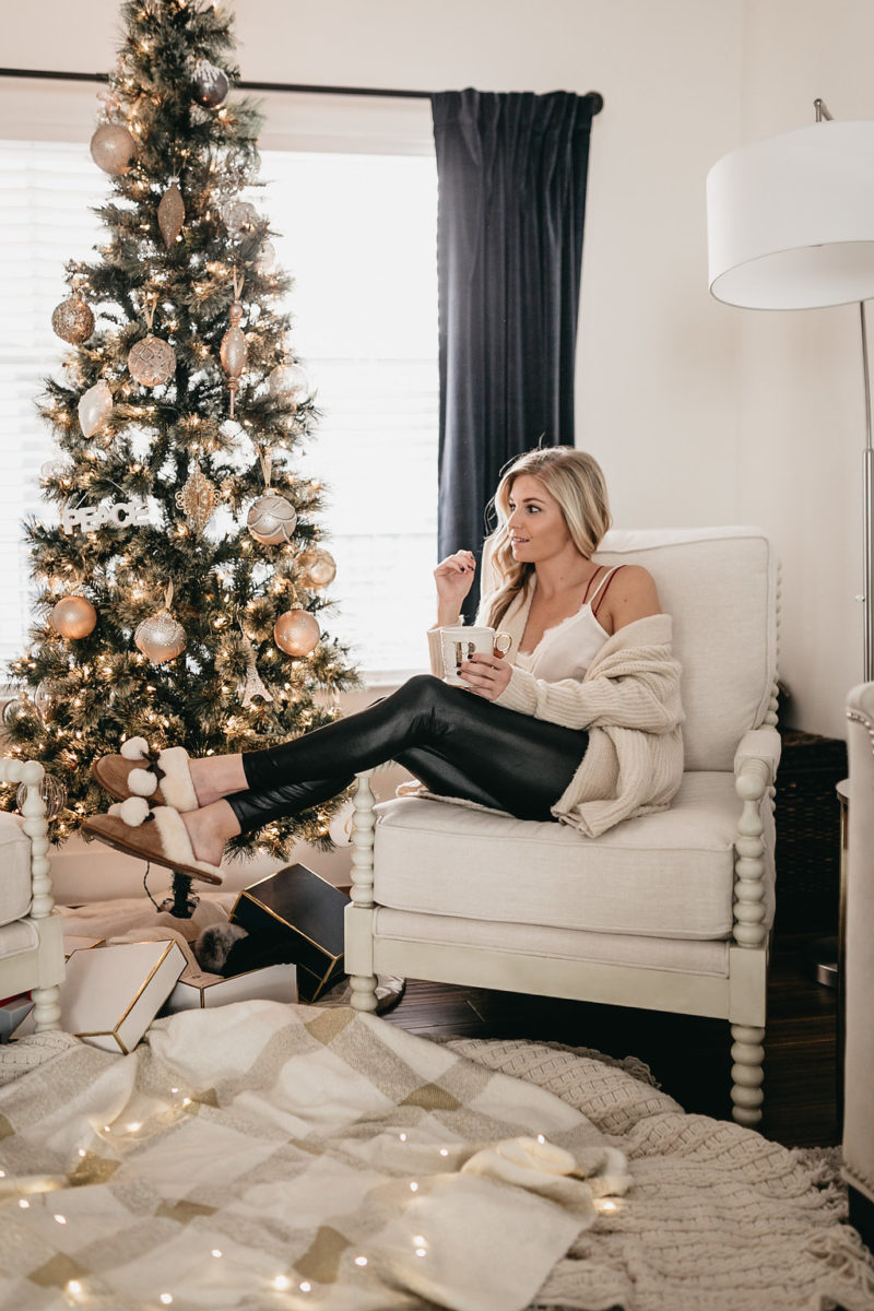 woman sitting on a white chair beside a christmas tree