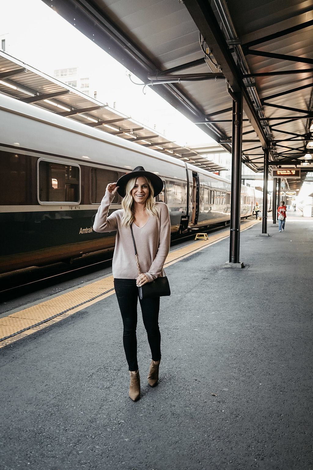 woman at the train station and wearing cardigan and black jeans