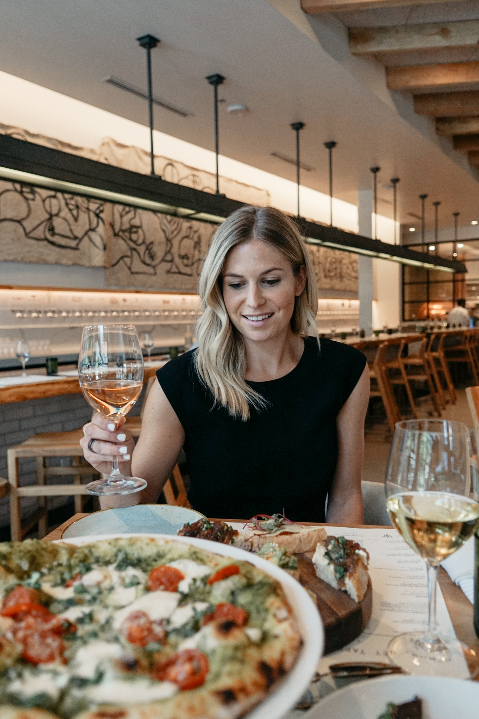 woman holdign a glass of wine and eating italina food on dallas summer 2018