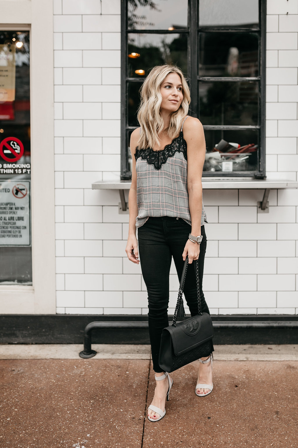 woman showing how to wear plaid, black pants, and black bag