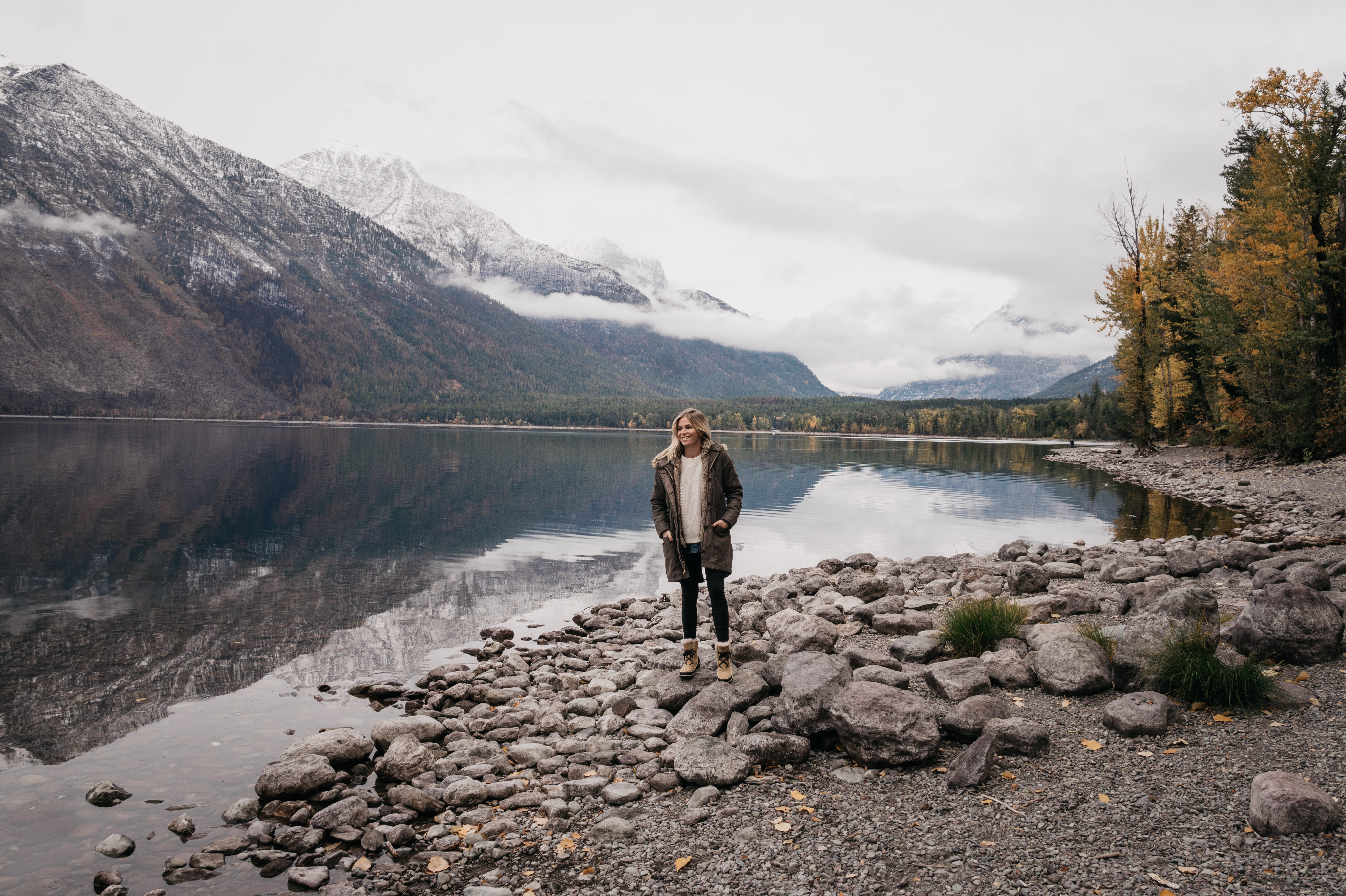 woman standing near the lake surrounded by mountains for fall in Montana