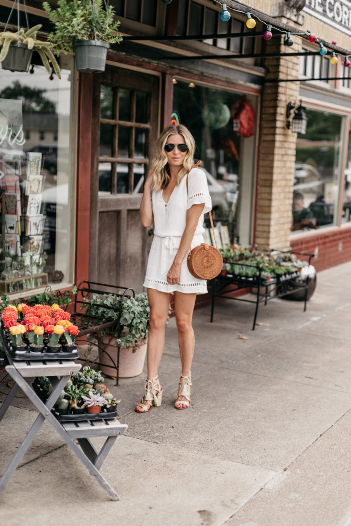 Brooke Burnett is wearing a white lace romper and woven circle bag