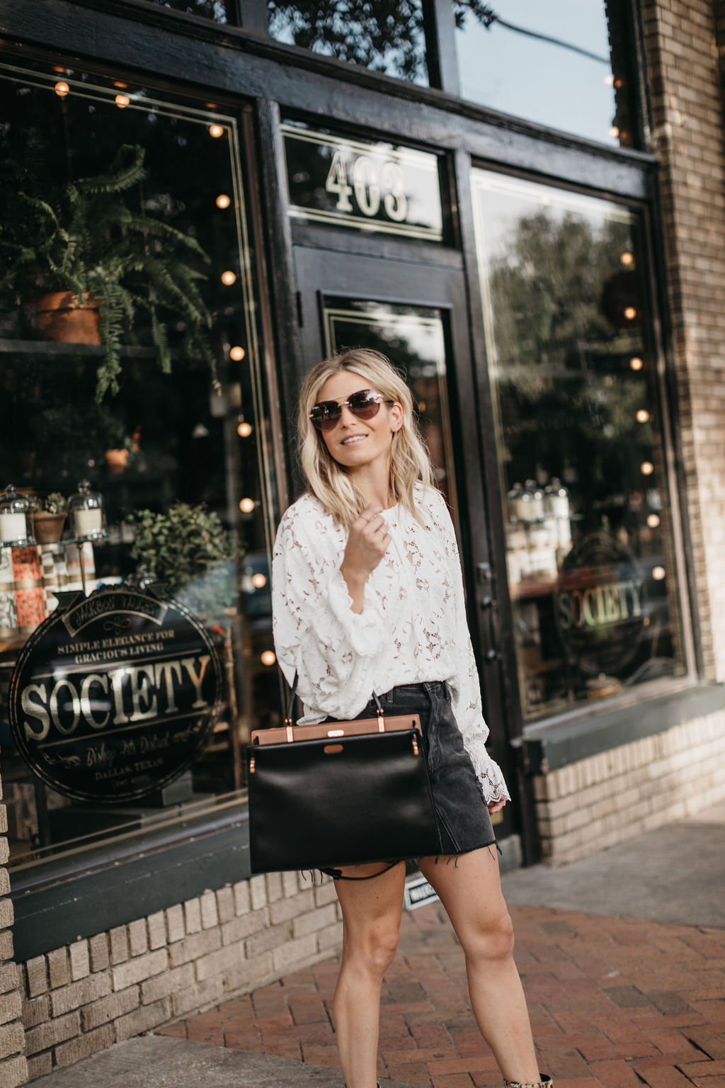 woman wearing white top, black skirt, and holding black bag SHOPBOP SPRING SALE 2020